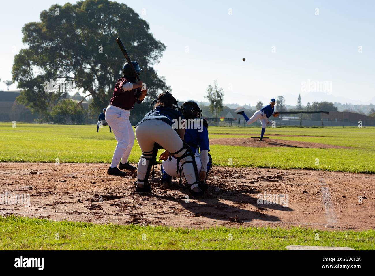 Verschiedene Baseballspielerinnen in Aktion auf sonnigem Baseballfeld während des Spiels Stockfoto