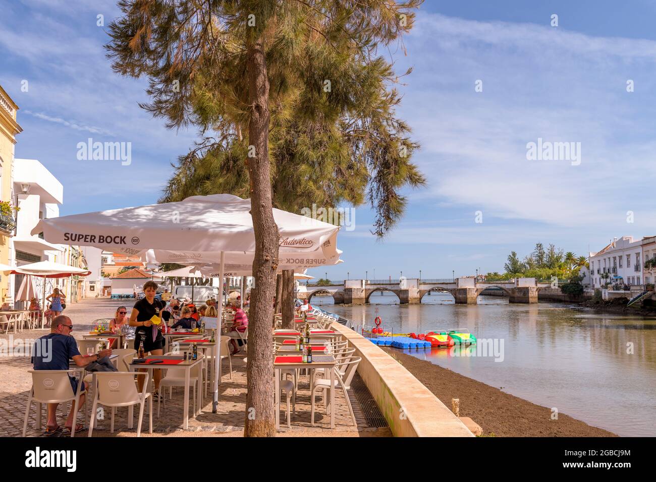 Riverside Cafe Restaurant am Fluss Gilao Tavira. Im Hintergrund ist die römische Brücke oder Ponte Romana de Tavira zu sehen. Tavira East Alga Stockfoto