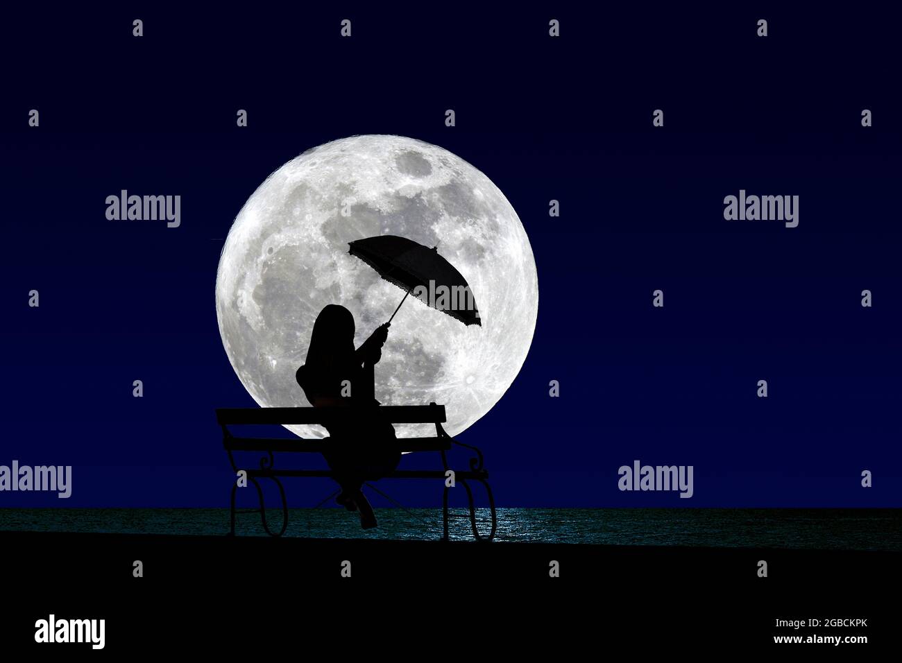 Mädchen / Frau sitzt auf einer Bank am Meer / Wasser mit Regenschirm silhouetted gegen einen Vollmond Stockfoto