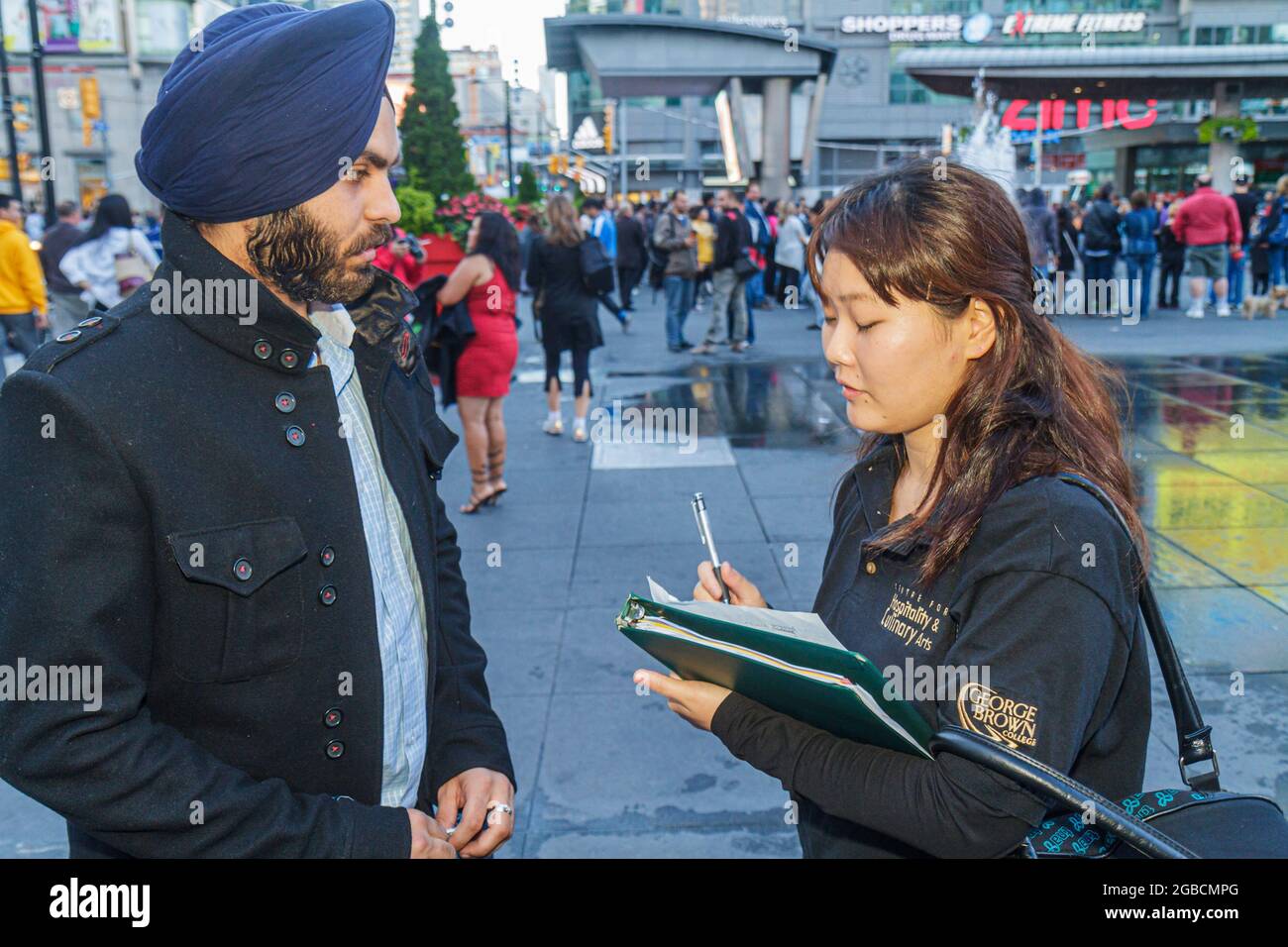 Toronto Kanada, Yonge Street Dundas Square öffentliche plaza, Umfrage Umfragen unter Turban Bart Sikh Tragen Dastar, asiatische Mann Frau weiblich Schreiben Interview Stockfoto