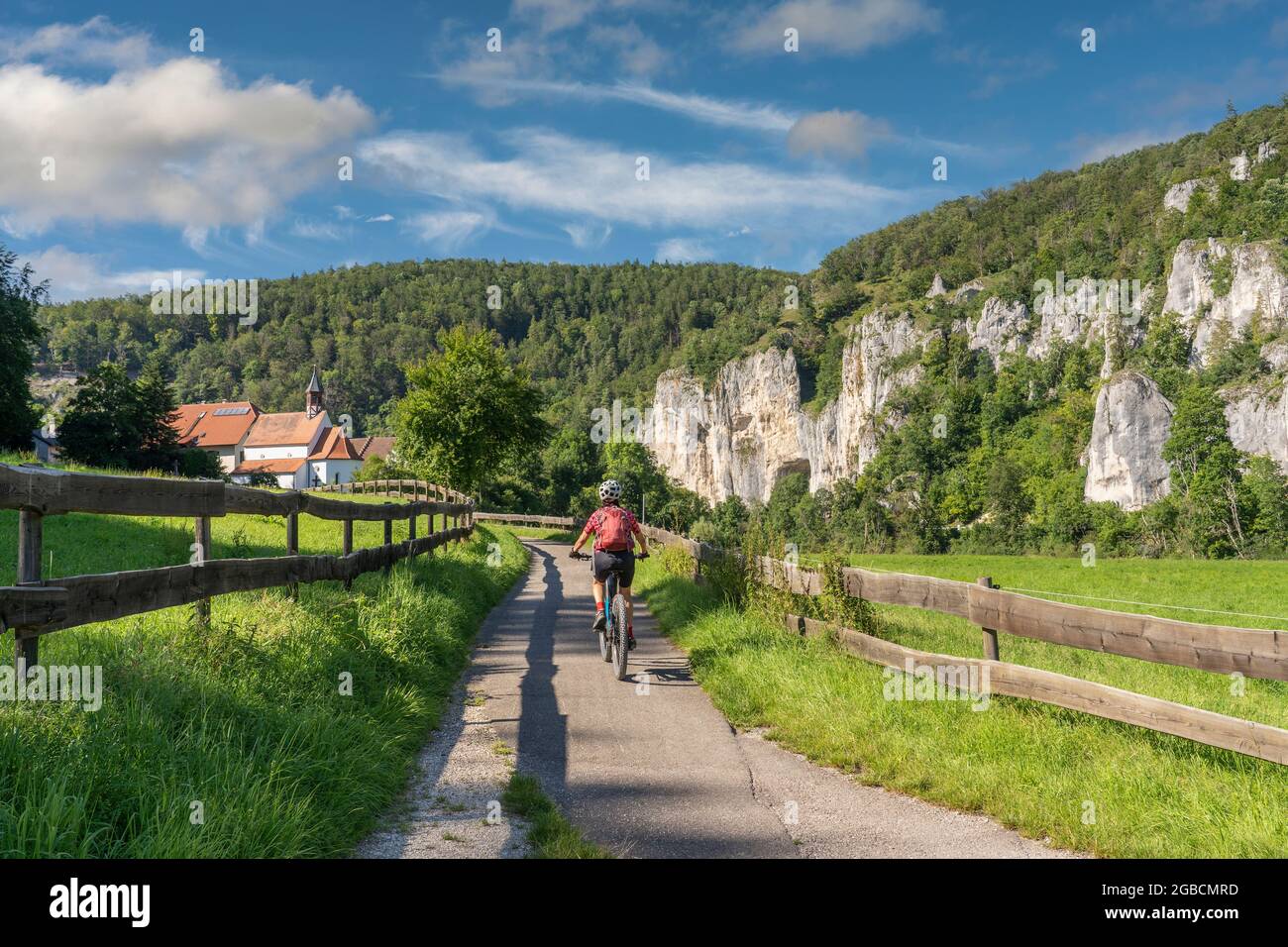 Schöne aktive Seniorin, die mit ihrem Elektro-Mountainbike im felsigen Oberen Donautal auf der Schwäbischen Alb zwischen Beuron und Sigmaring unterwegs ist Stockfoto