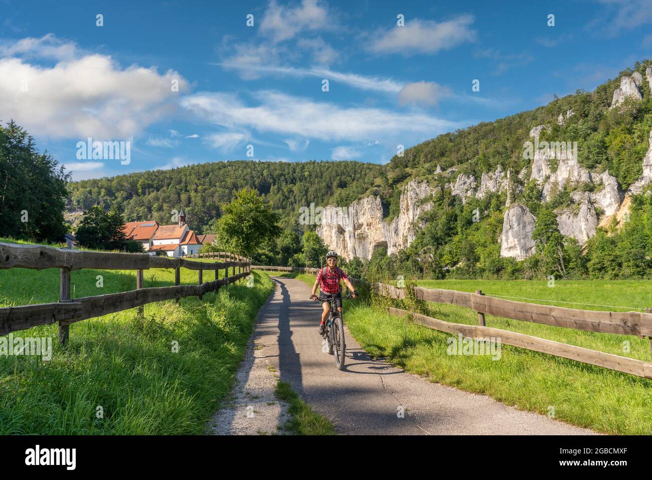 Schöne aktive Seniorin, die mit ihrem Elektro-Mountainbike im felsigen Oberen Donautal auf der Schwäbischen Alb zwischen Beuron und Sigmaring unterwegs ist Stockfoto
