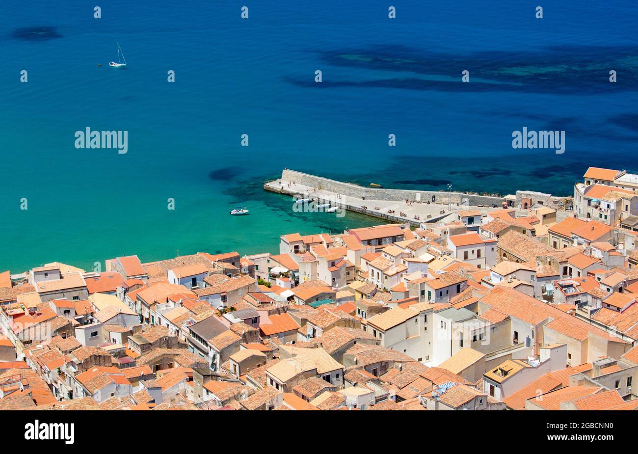 Cefalù, Palermo, Sizilien, Italien. Blick über die Ziegeldächer der Altstadt von La Rocca, das türkisfarbene Wasser des Tyrrhenischen Meeres dahinter. Stockfoto