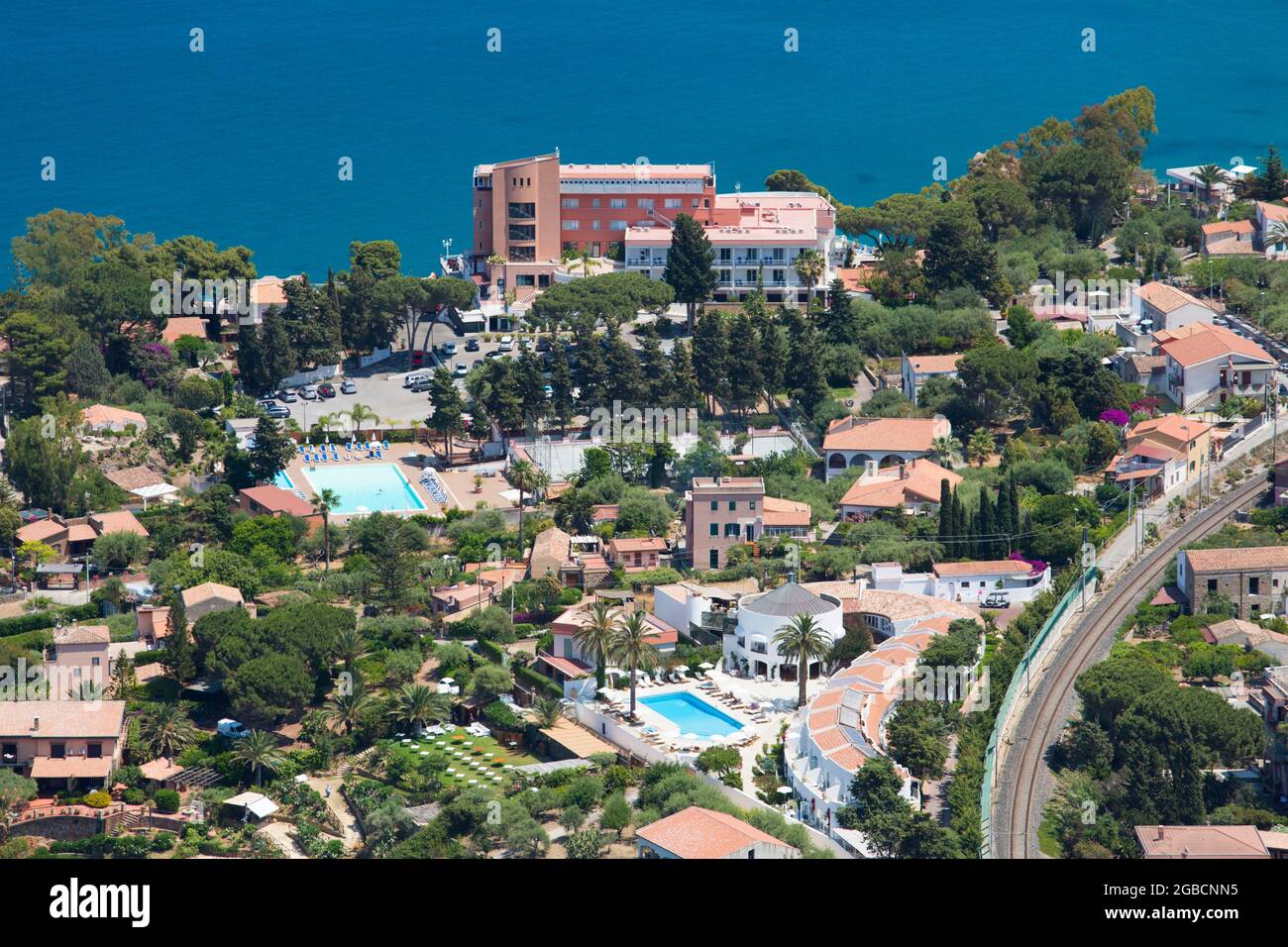 Cefalù, Palermo, Sizilien, Italien. Blick auf die Hotelgärten vom Gipfel von La Rocca, dem noch türkisfarbenen Wasser der Calura Bay dahinter. Stockfoto