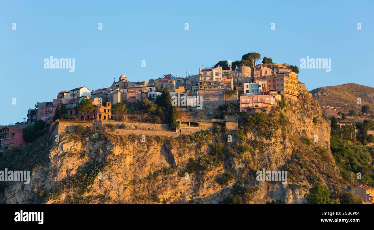 Taormina, Messina, Sizilien, Italien. Blick auf das hübsche mittelalterliche Dorf Castelmola, Sonnenaufgang, prekär thronende Häuser, die sich an einer Klippe Klammern. Stockfoto