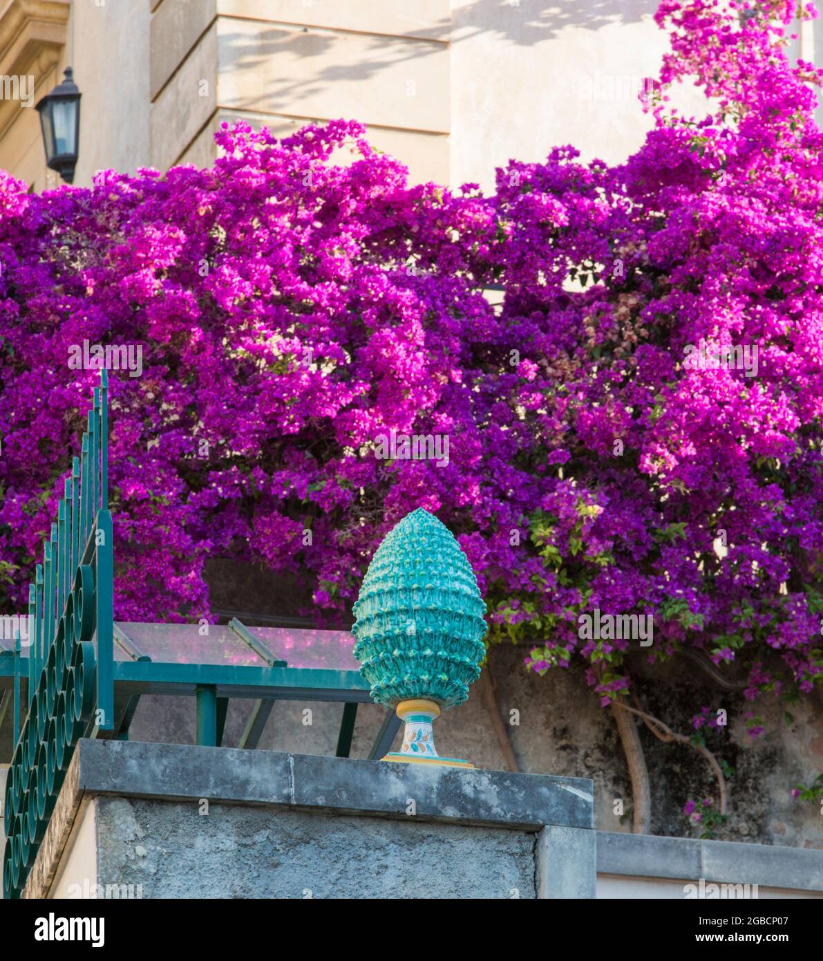 Taormina, Messina, Sizilien, Italien. Rosafarbene Bougainvillea schmückt eine Straßenecke der Altstadt hinter einer exquisiten Keramikvase in Form eines Pinienkegels. Stockfoto