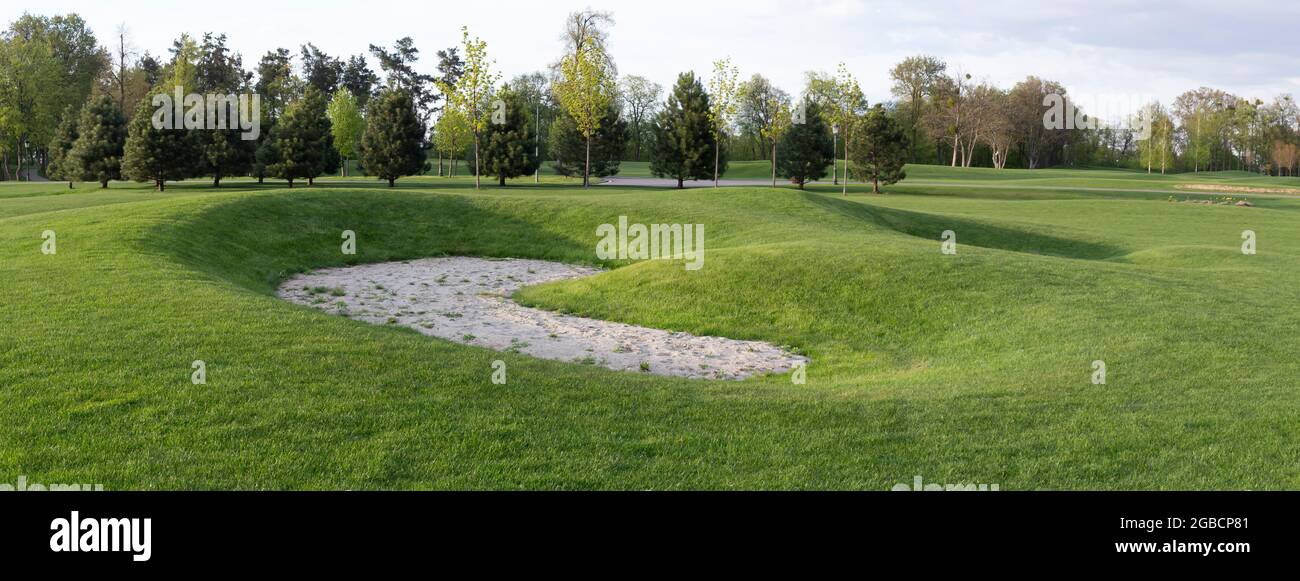 Golfplatz, verlassene Sandfalle. Panorama des Golfplatzes, Rasengras und der Bäume, die auf dem Gebiet wachsen. Golfplatz Stockfoto