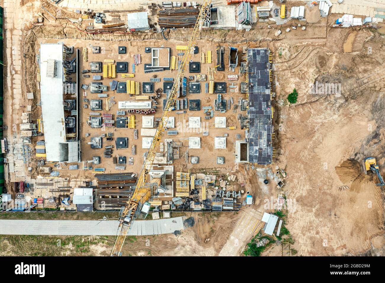 Mehrstufige Parkgarage im Bau. Bau der Fundamente auf der Baustelle mit einem gelben Kran. Luftaufnahme von oben Stockfoto