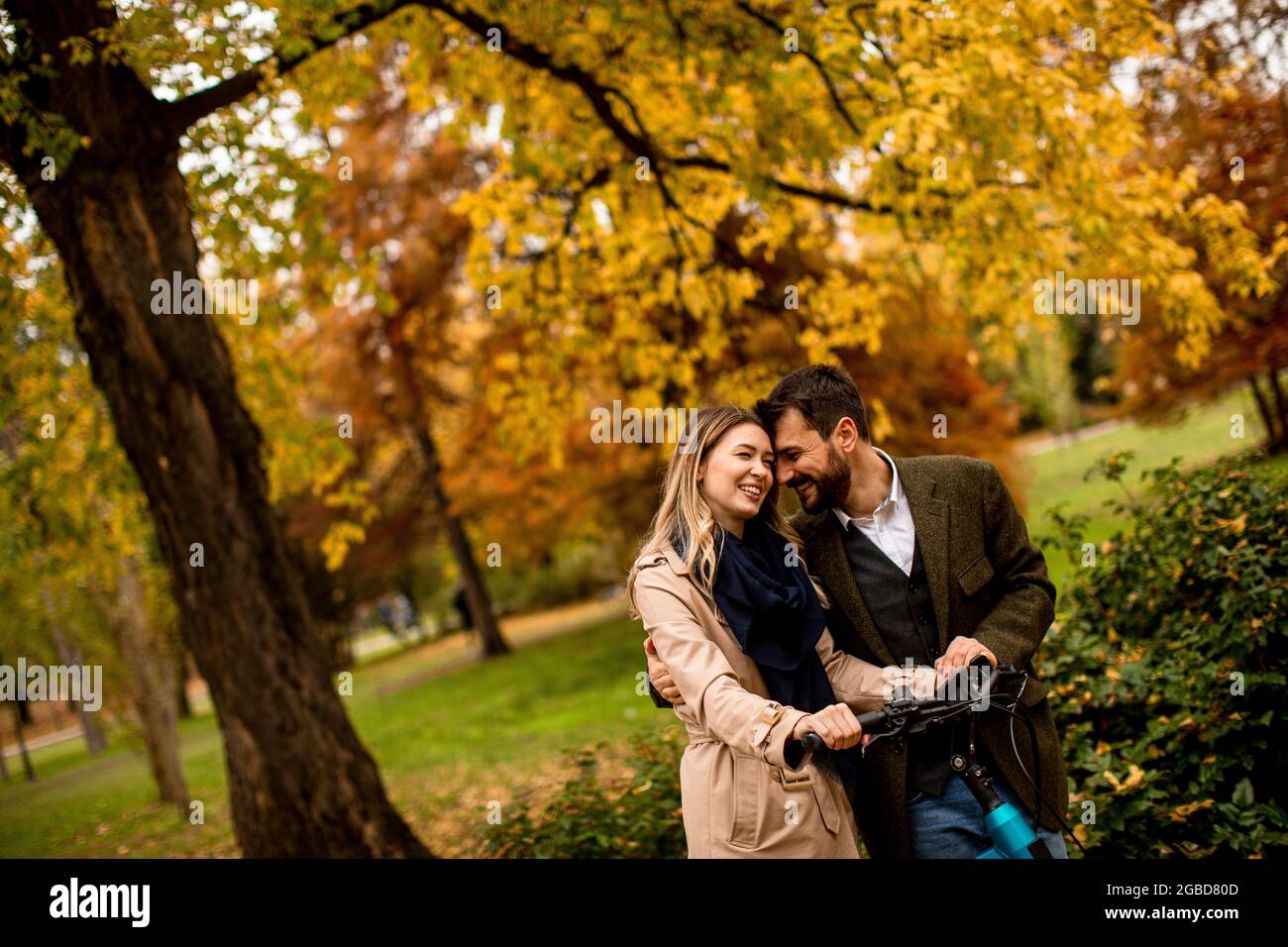 Schönes junges Paar im Herbstpark mit Elektrofahrrad Stockfoto