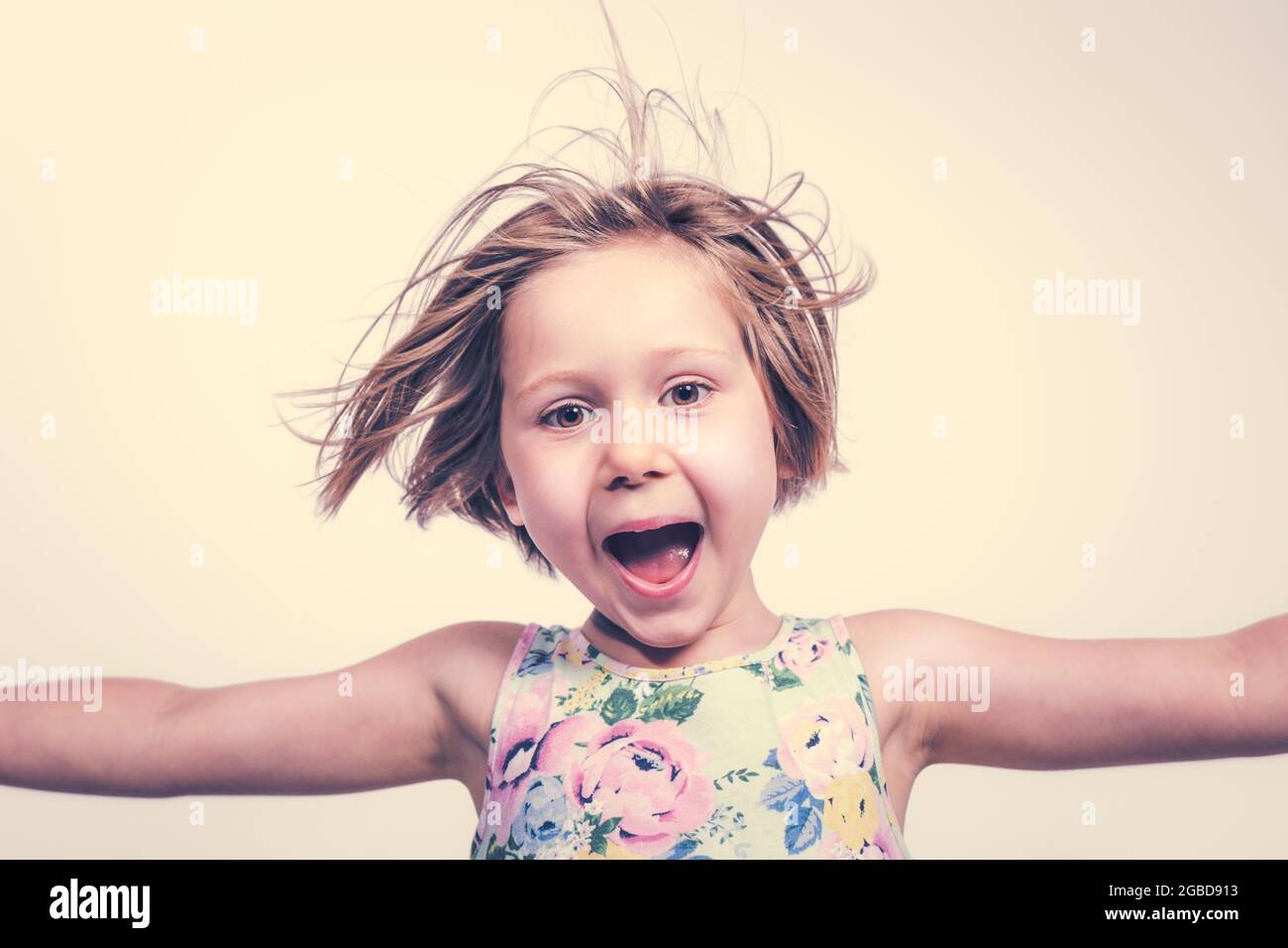 Lächelndes und fröhliches kleines Mädchen mit offenen Armen. Stockfoto