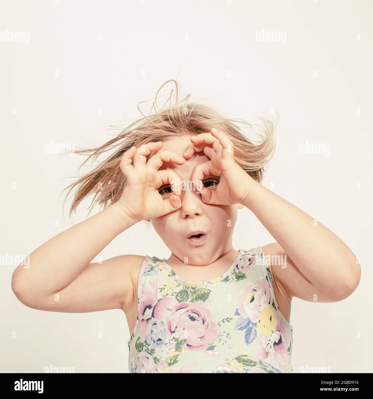 Kleines Mädchen mit den Händen über den Augen, um eine Brille zu simulieren Stockfoto