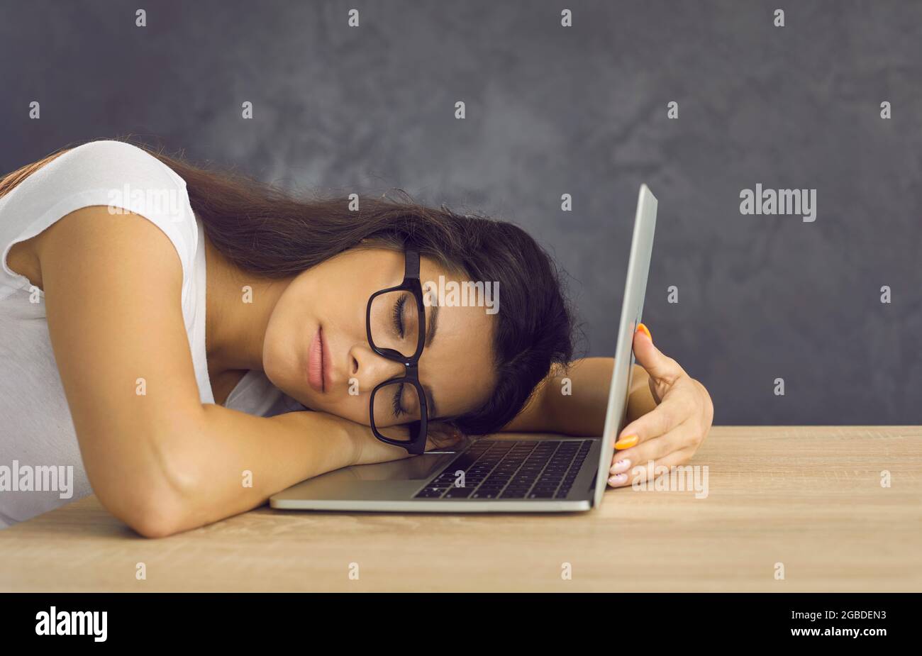 Müde, erschöpfte Studentin, die mit ihrem Laptop am Schreibtisch schlief Stockfoto