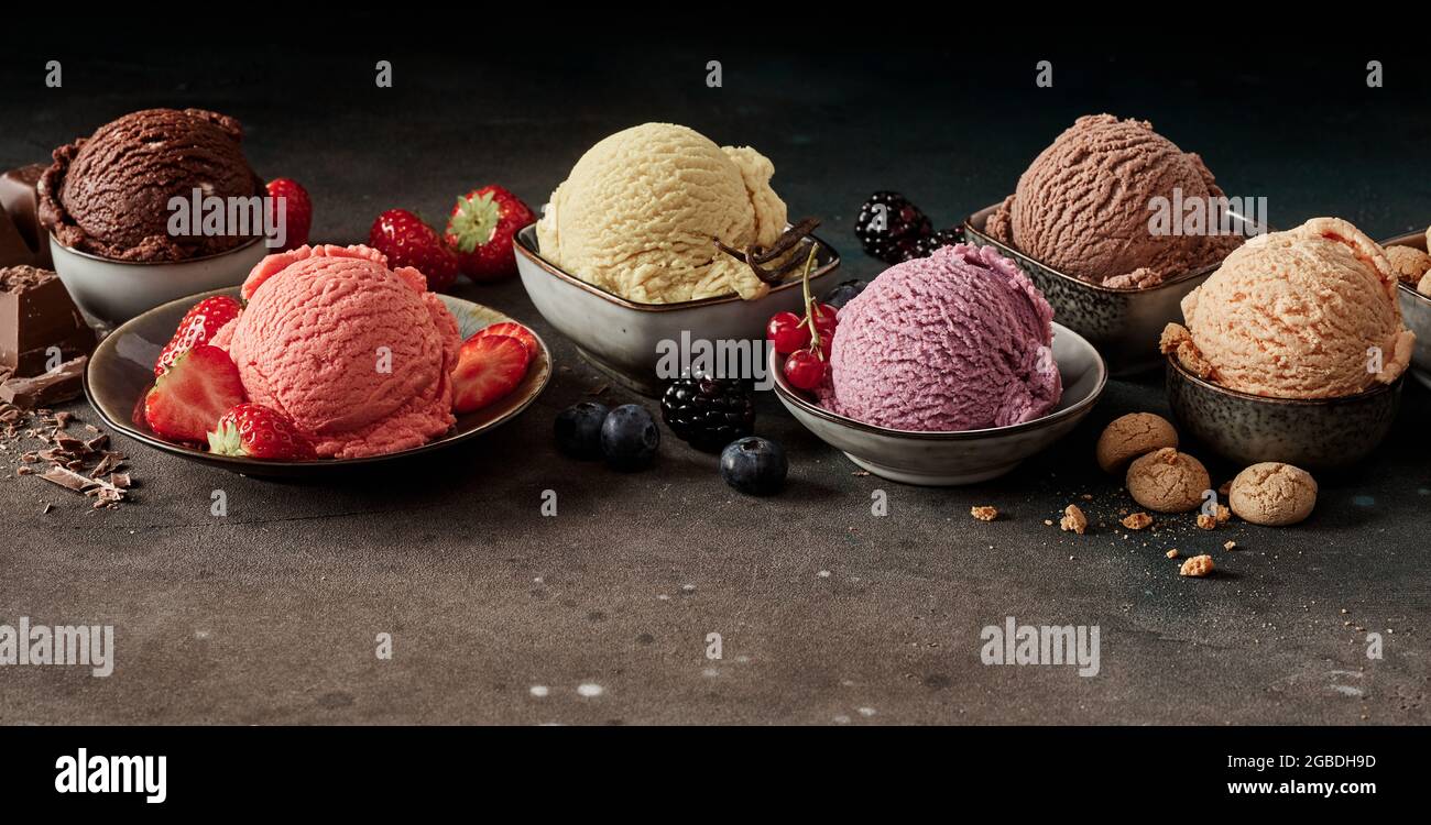 Set von schmackhaften appetitlichen Eisschaufeln in verschiedenen Farben und Gefälligkeiten mit Schokolade und Beeren in Schalen Stockfoto