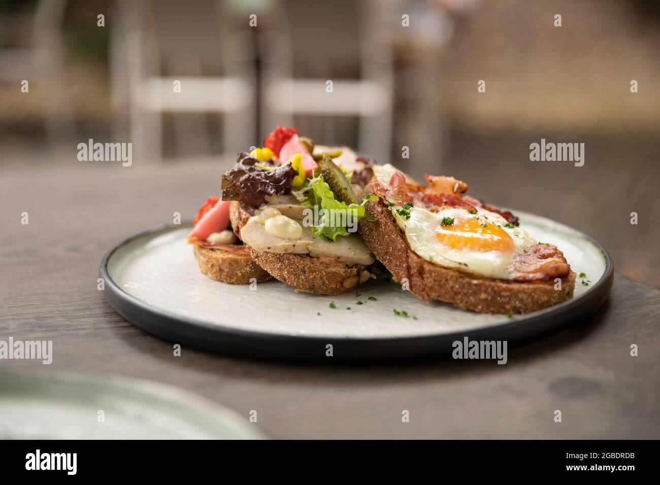 Gesundes hausgemachtes Club-Sandwich-Gericht mit frischen Zutaten wie Tomaten, Salat, Salat, Speck, Blumenkohl und Huhn und einem sonnigen Ei auf einem Stockfoto