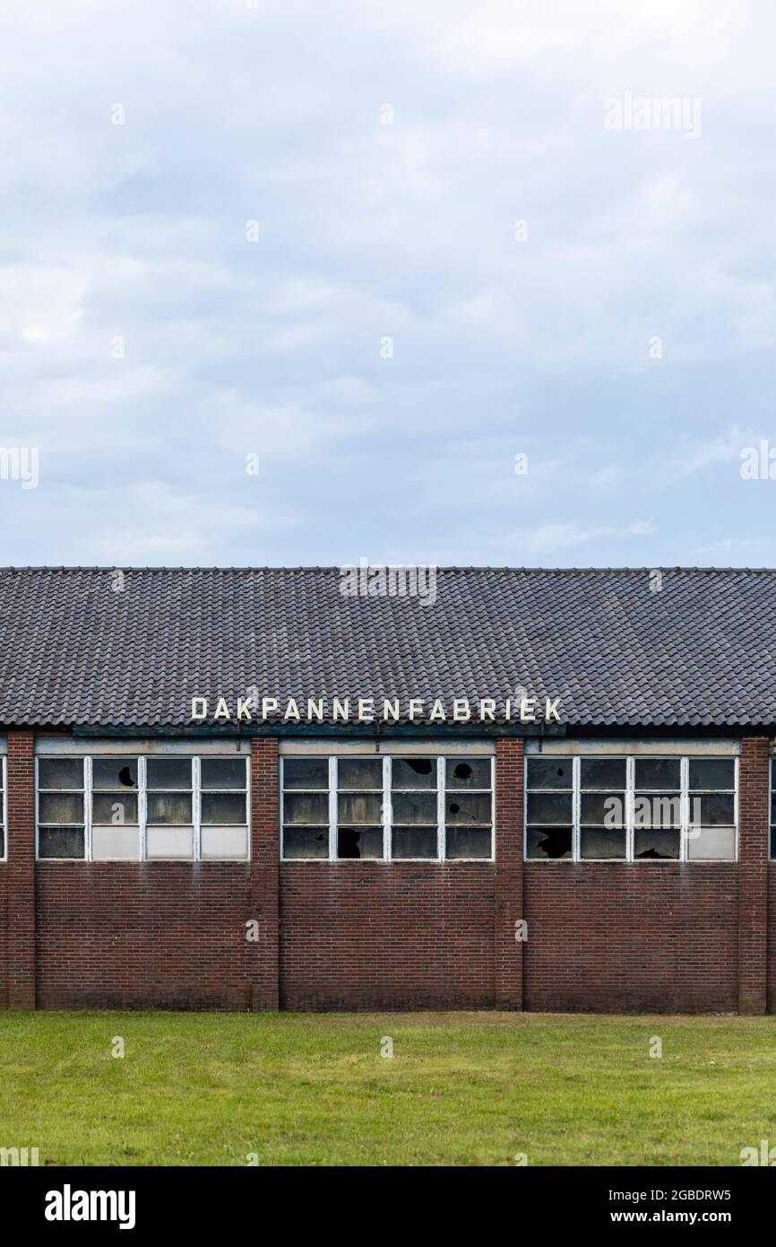 Thorn, Niederlande, 24. Juli 2021. Alte Dachziegelfabrik mit kaputten Glasfenstern und traditionellen welligen Dachziegeln in Limburg. Vertikale Sho Stockfoto