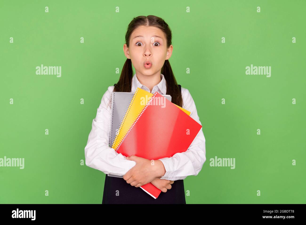 Foto Porträt schulmädchen starren erstaunt halten Buch in der Schulbibliothek isoliert pastellgrün Hintergrund Stockfoto