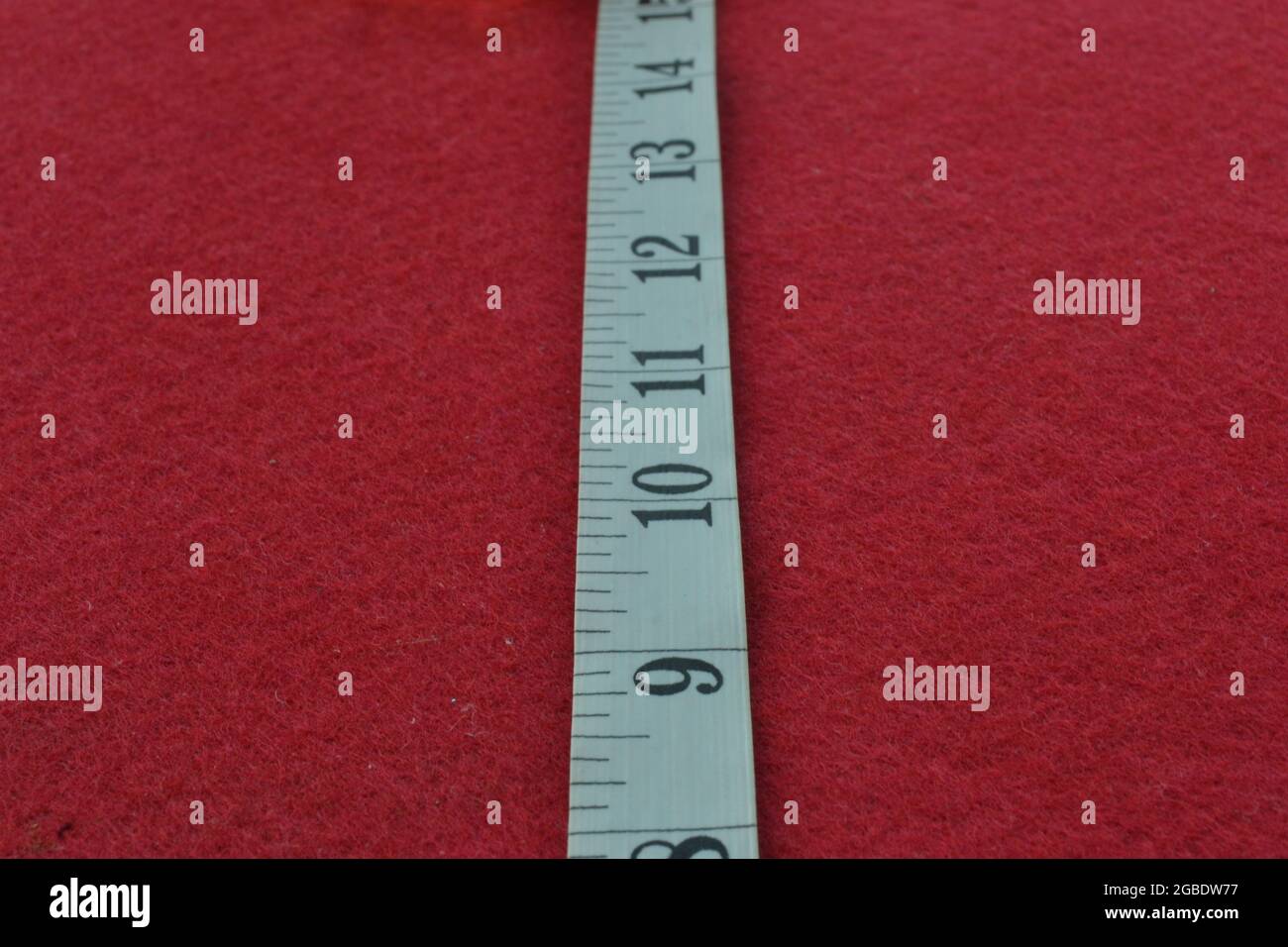 Weißes Maßband auf rotem Hintergrund mit den Zahlen messen Stockfoto
