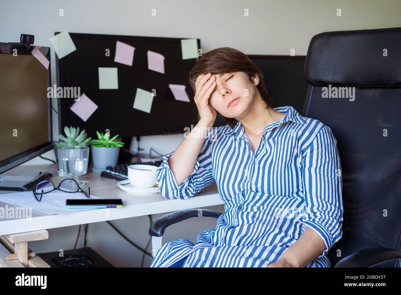Müde fühlen. Frustrierte Geschäftsfrau, die während der Online-Arbeit am pc eine Pause einnahm. Unter Kopfschmerzen leidend, sitzt der erschöpfte Arbeiter mit geschlossenen Augen Stockfoto
