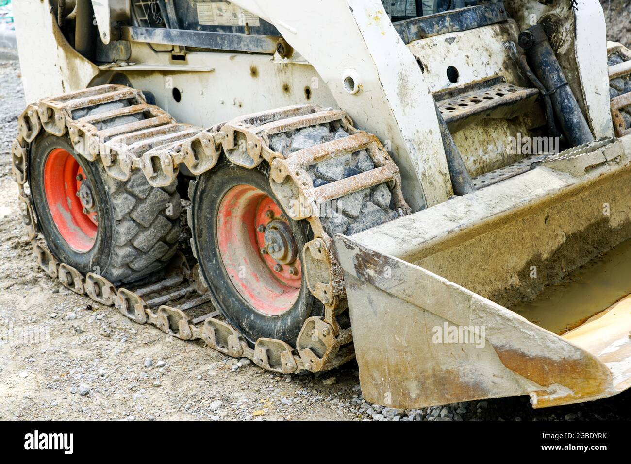 Verschmutzter Rutschlader oder Bobcat mit Metallspuren auf Gummireifen Stockfoto