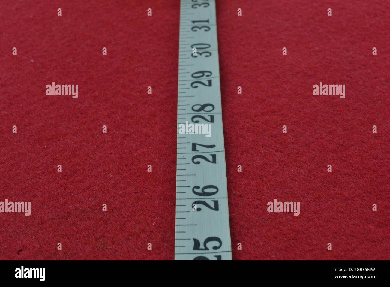 Weißes Maßband auf rotem Hintergrund mit den Zahlen messen Stockfoto