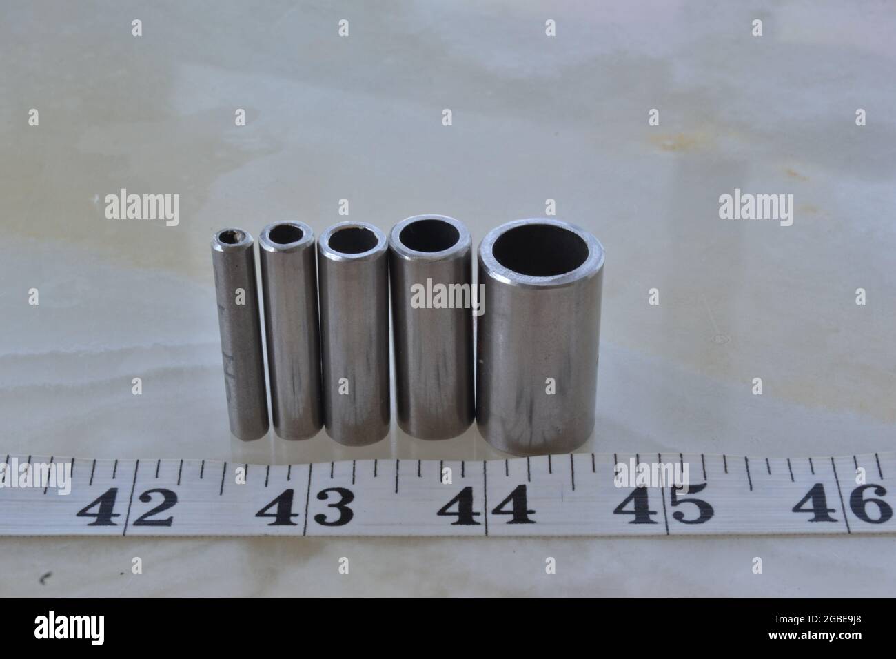 Vier Rohre aus Edelstahl in verschiedenen Durchmessern mit Messband Stockfoto