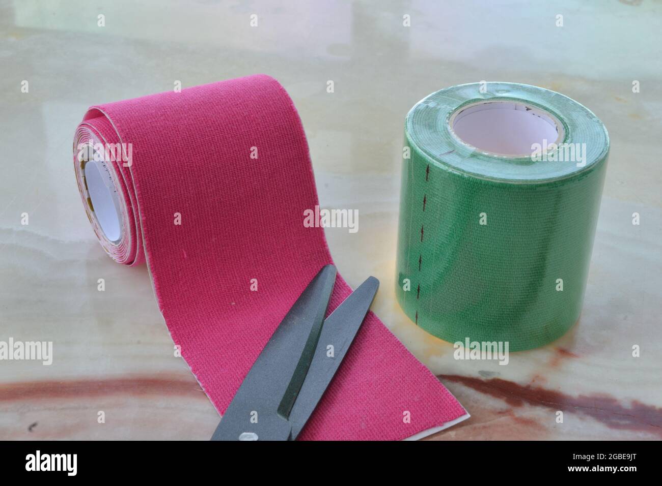 Tape Bandagen mit schwarzer Schere grün und magenta Tape-Applikation gegen Schmerzen Stockfoto