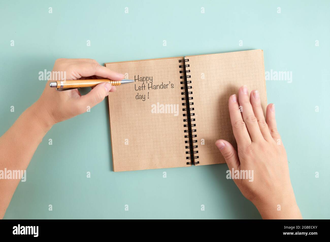 Happy Left Hander's Day. Halten Sie den Stift mit der linken Hand und schreiben Sie Text. Stockfoto