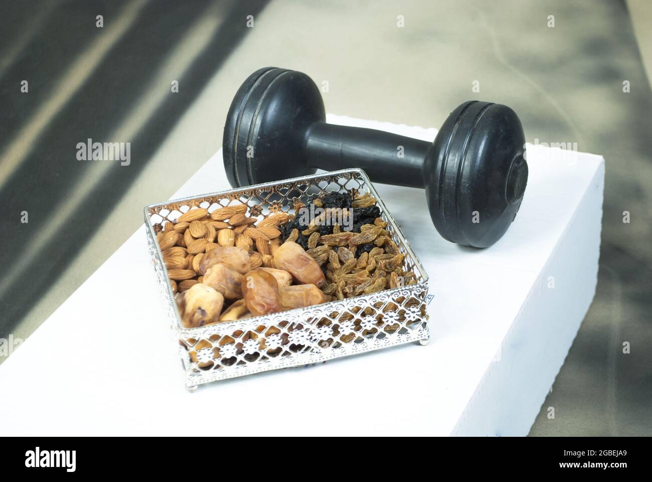 Gym Workout Food Bio gesund Mix Trockenfrüchte mit Hantel goldene und schwarze Rosinen Datteln Mandeln Übungskonzept Raum für Text Stockfoto