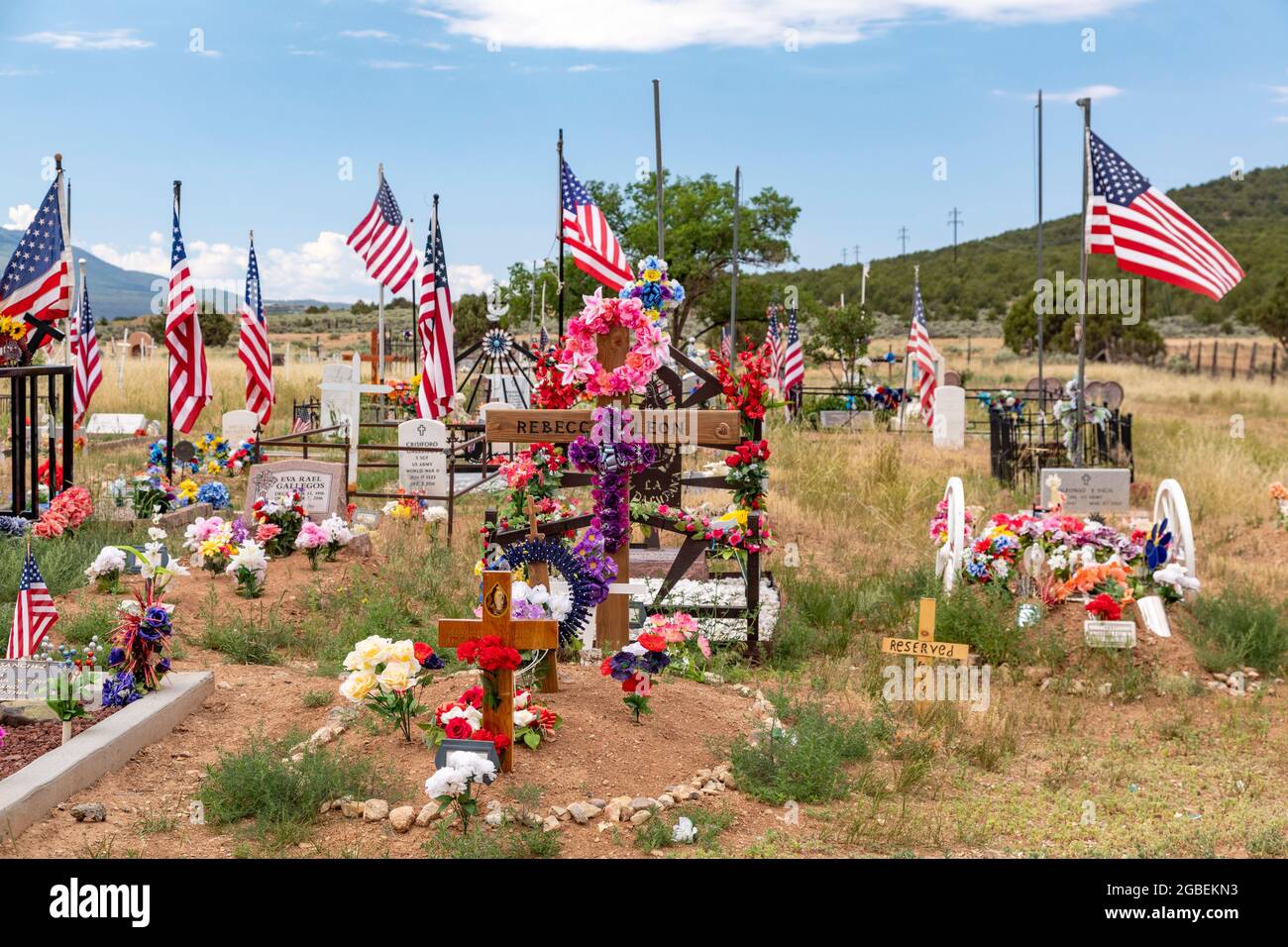 Cerro, New Mexico - EIN ländlicher Friedhof, auf dem Gräber mit Blumen und Fahnen geschmückt sind. Stockfoto