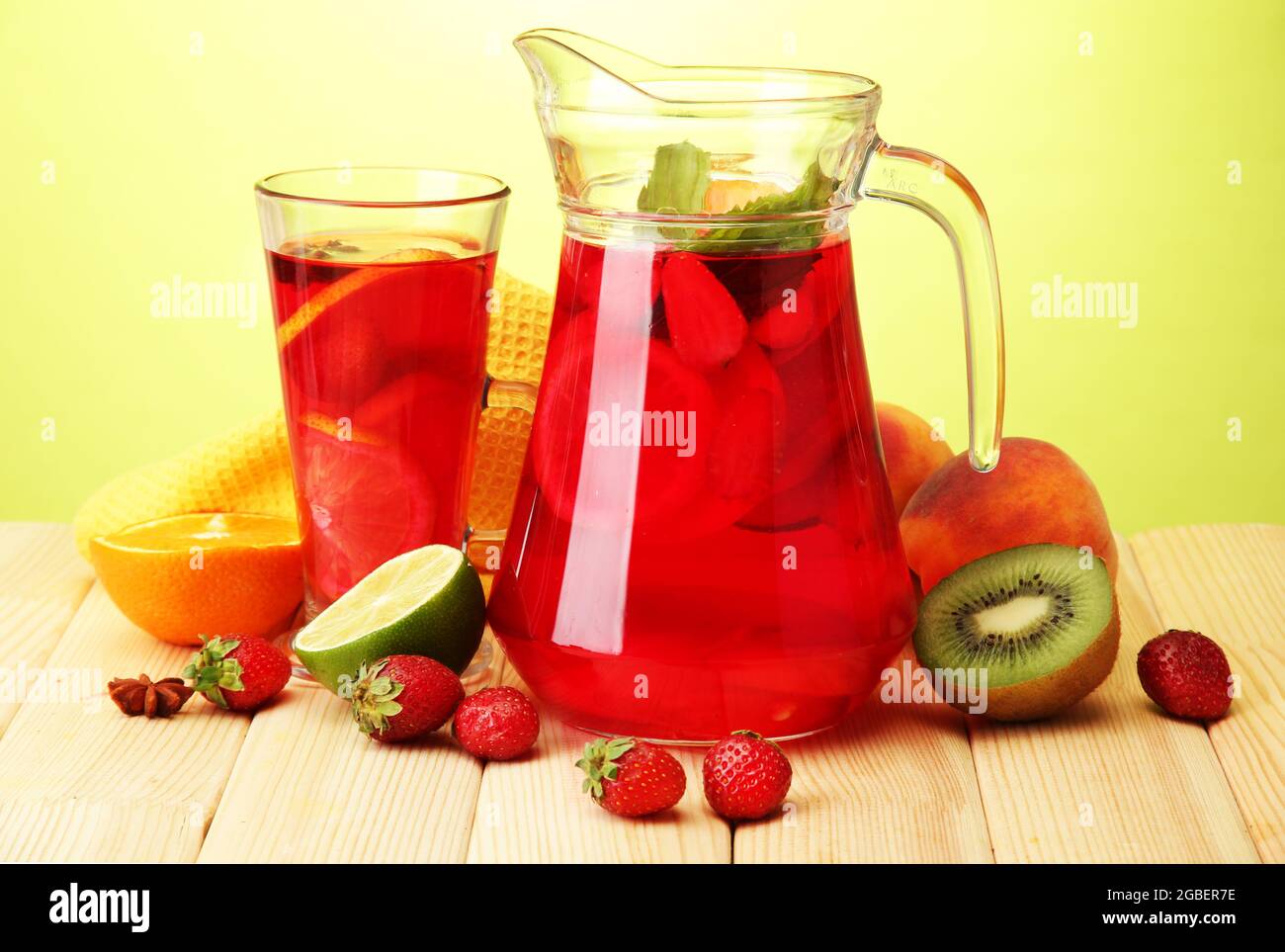 Sangria in Krug und Glas mit Früchten, auf Holztisch, auf grünem  Hintergrund Stockfotografie - Alamy
