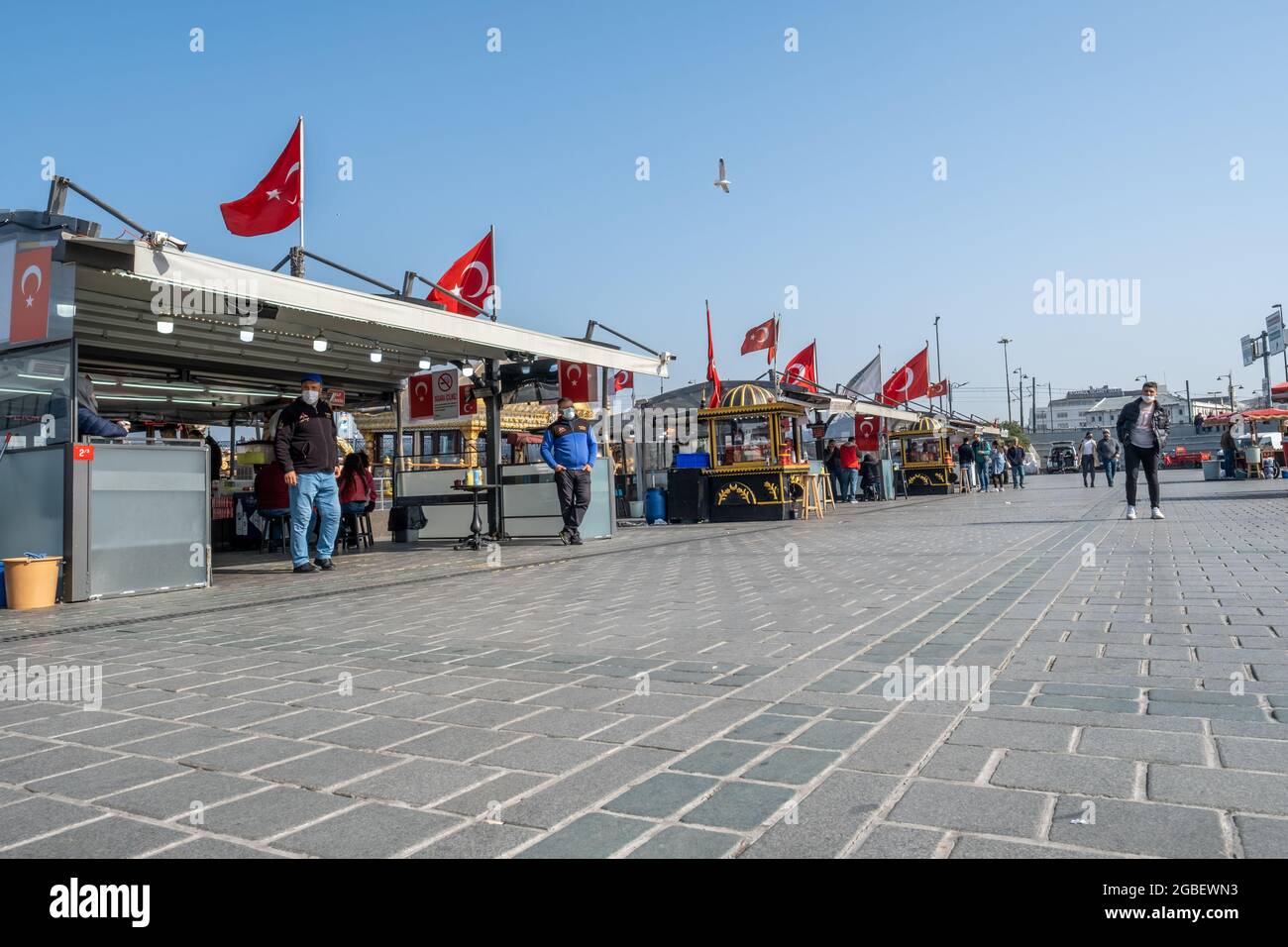 Eminonu, Istanbul, Türkei - 02.27.2021: Fast leere Bootsrestaurants mit Fischbraten auf dem Eminonu-Platz mit türkischen Flaggen Stockfoto