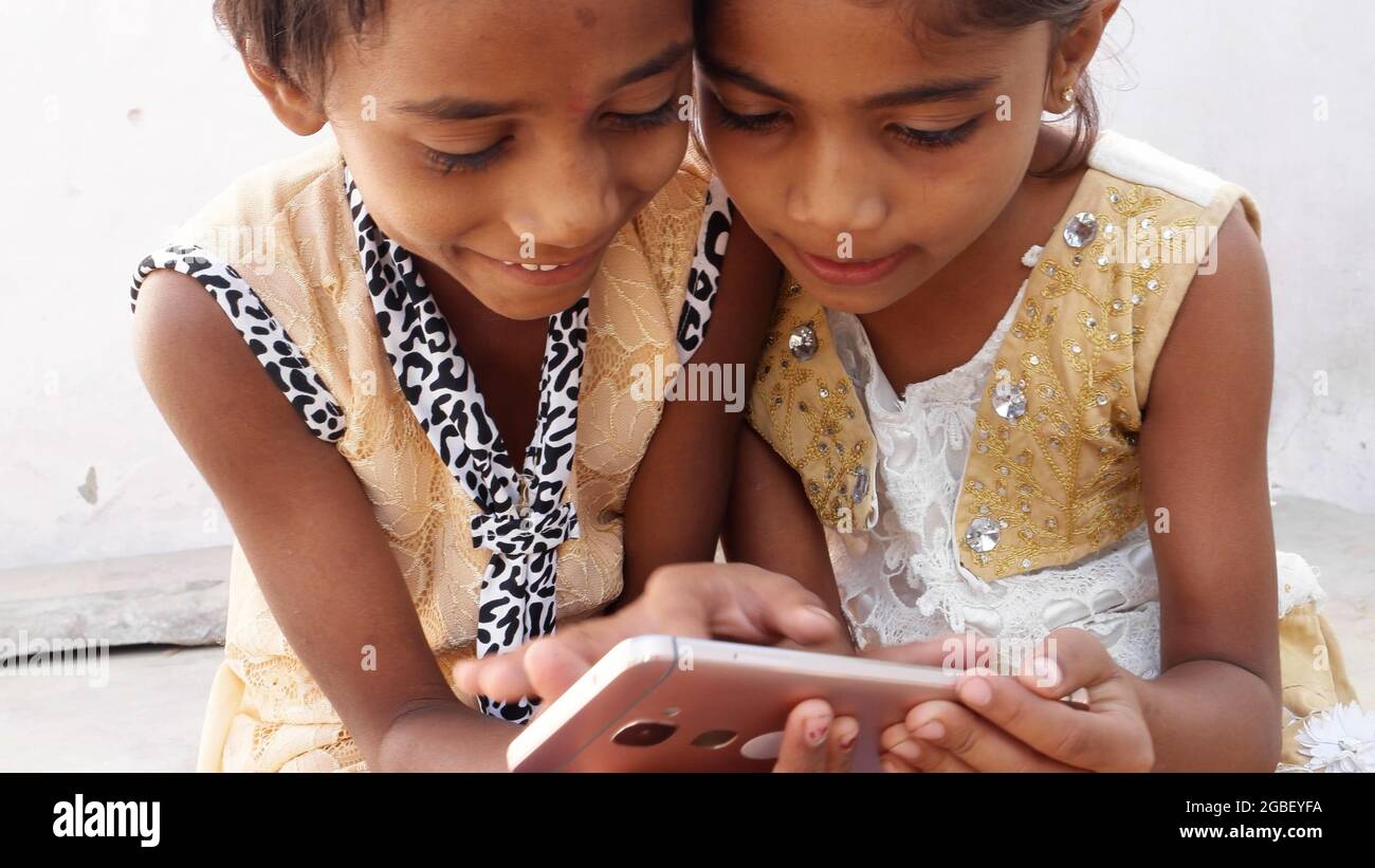 Kinder, die draußen sitzen und Cartoons auf einem Tablet ansehen Stockfoto
