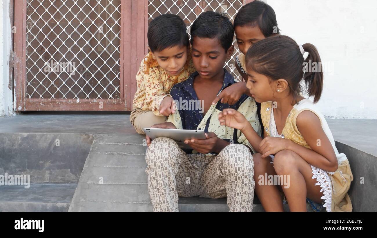 Kinder, die draußen sitzen und sich gemeinsam Cartoons auf einem Tablet ansehen Stockfoto