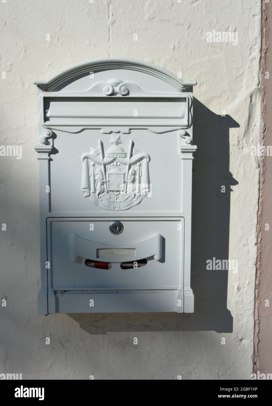 Vertikale Nahaufnahme eines grauen Vintage-Postfachs mit einem Wappen an der Wand Stockfoto