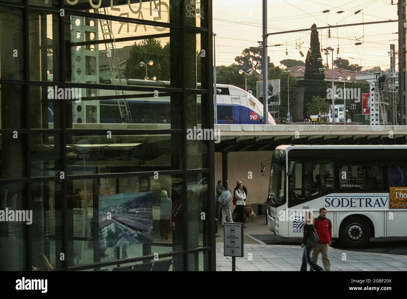 Bild des Bahnhofs und Busbahnhofs von Toulon am frühen Morgen mit Passagieren, die bereit sind, in einen Bus mit einem SNCF-Zug im Hintergrund einzusteigen. Toulon ist ein c Stockfoto