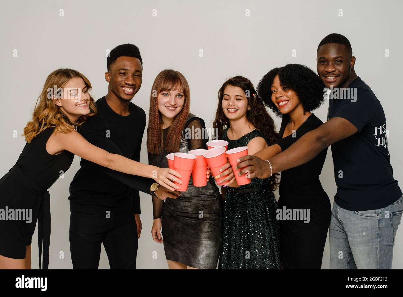 Taille bis von sechs Freunden Spaß und Alkohol trinken während der Neujahrsparty, isoliert auf weißem Hintergrund. Eine Gruppe von fröhlichen Freunden von verschiedenen Stockfoto