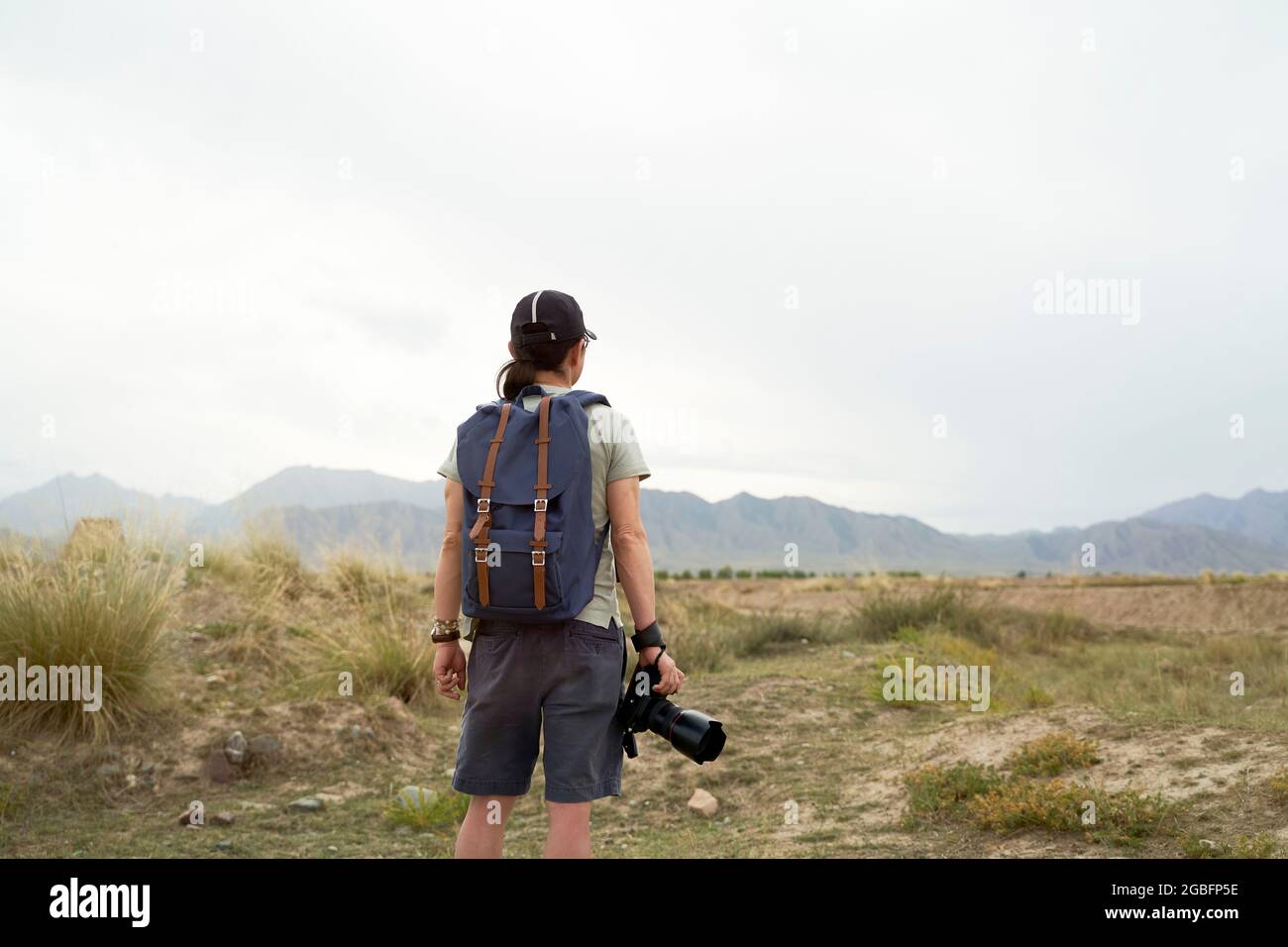 Rückansicht eines asiatischen Fotografen mit Rucksack und Kamera in der Hand Stockfoto