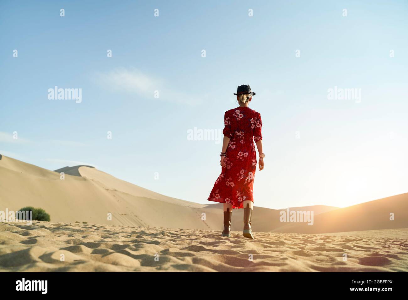 Rückansicht einer asiatischen Frau, die unter blauem Himmel in der Wüste läuft Stockfoto