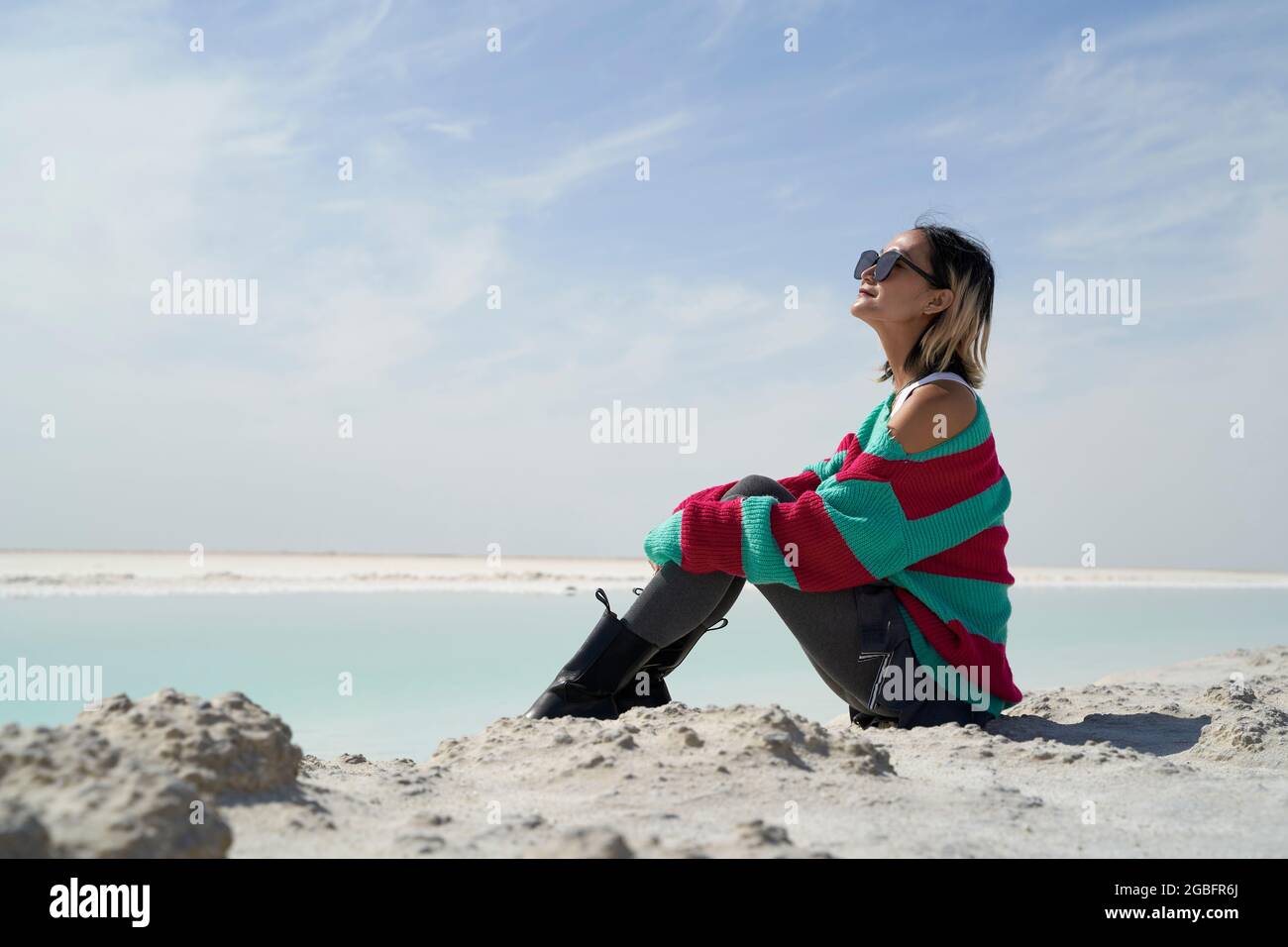 Seitenansicht der asiatischen Touristendame, die an einem Salzsee sitzt, mit Blick auf die Aussicht Stockfoto