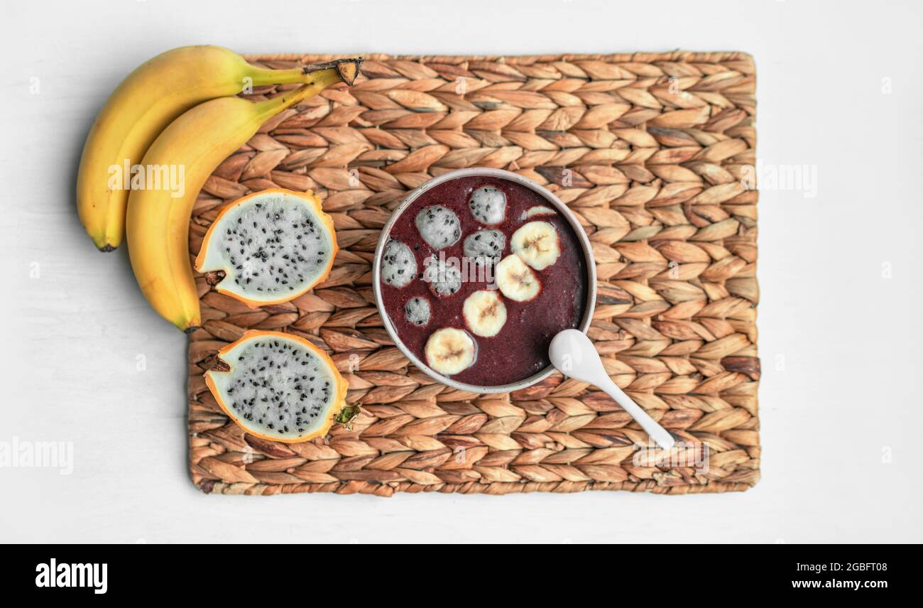 Acai Smoothie Schüssel mit frischen Pitaya-Kugeln und geschnittenen Bananen Belag auf gefrorenen Leckerbissen. Gesundes Bio-Frühstück Blick von oben zu Hause Stockfoto