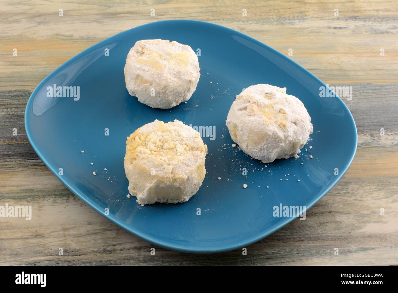 Griechische Mandel-Kourabiedes-Kekse auf blauem Dessertteller auf dem Tisch Stockfoto