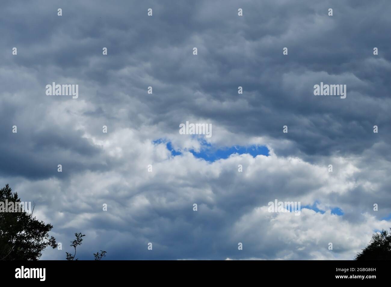 Ein Fragment des Himmels, bedeckt mit dicken Regenwolken und einem Schimmer blauen Himmels. Eine Veränderung des Wetters. Stockfoto