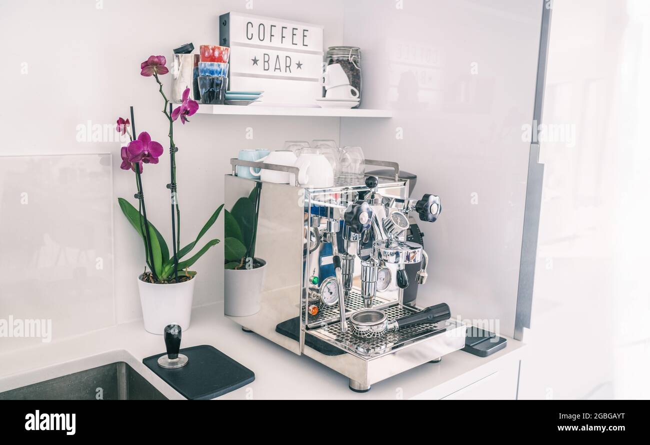 Heim Küche Dekor Kaffeebar für Espressomaschine auf der Arbeitsplatte, modernes Apartment-Wohnzimmer, Wandregale, Orchideenblume, Indoor-Lifestyle Stockfoto