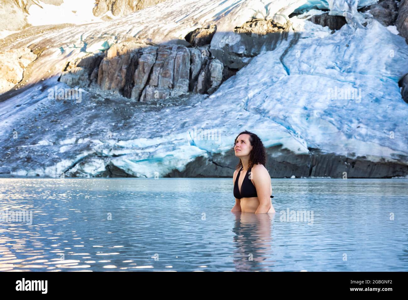 Abenteuerliche weißkaukasische Erwachsene Frau Schwimmen im eiskalter Gletschersee Stockfoto