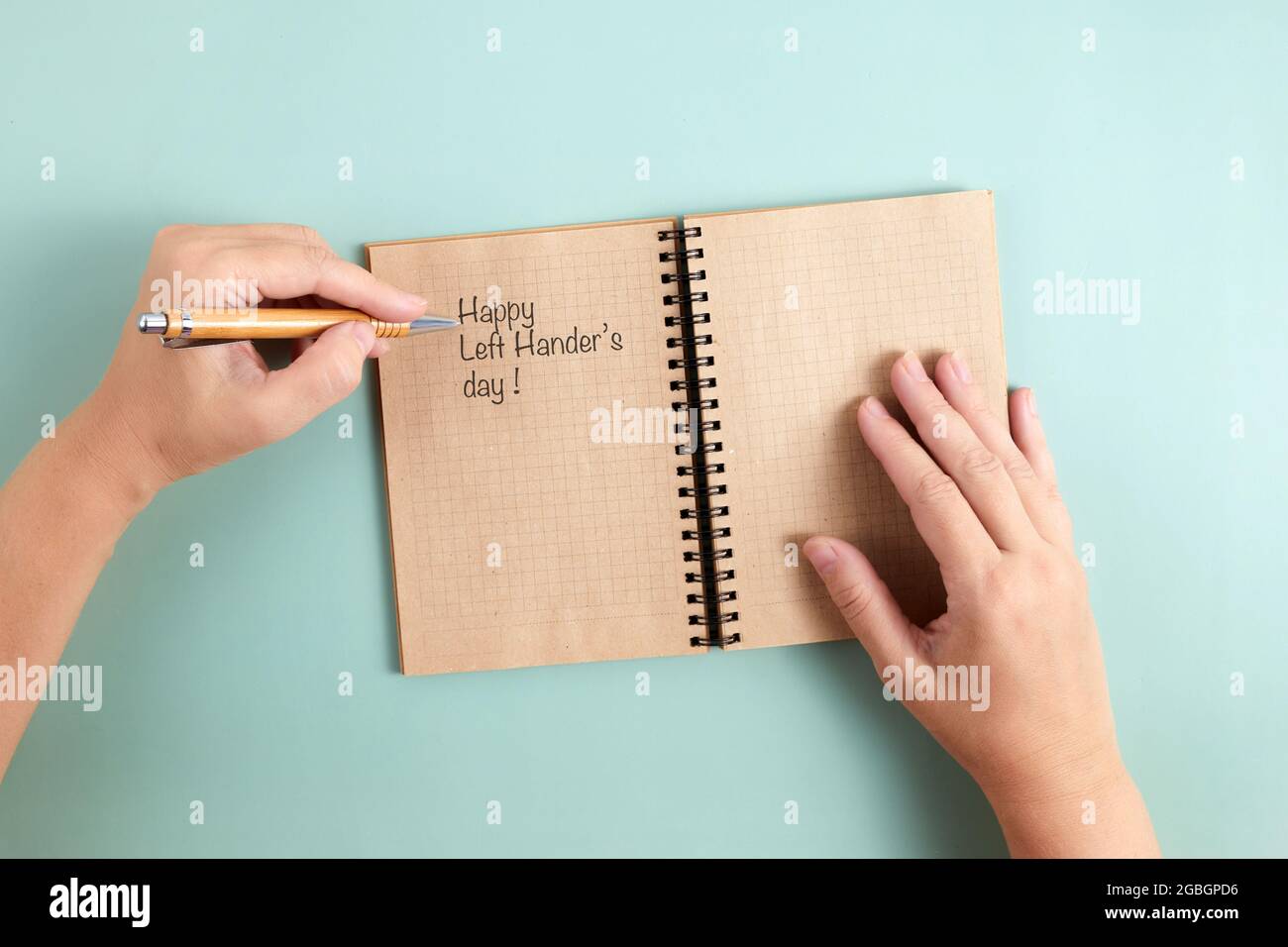 Happy Left Hander's Day. Halten Sie den Stift mit der linken Hand und schreiben Sie Text. Stockfoto