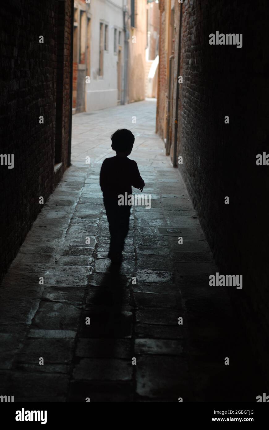 Silhouette eines Kindes, das in einem dunklen Korridor läuft - depressiv Stockfoto