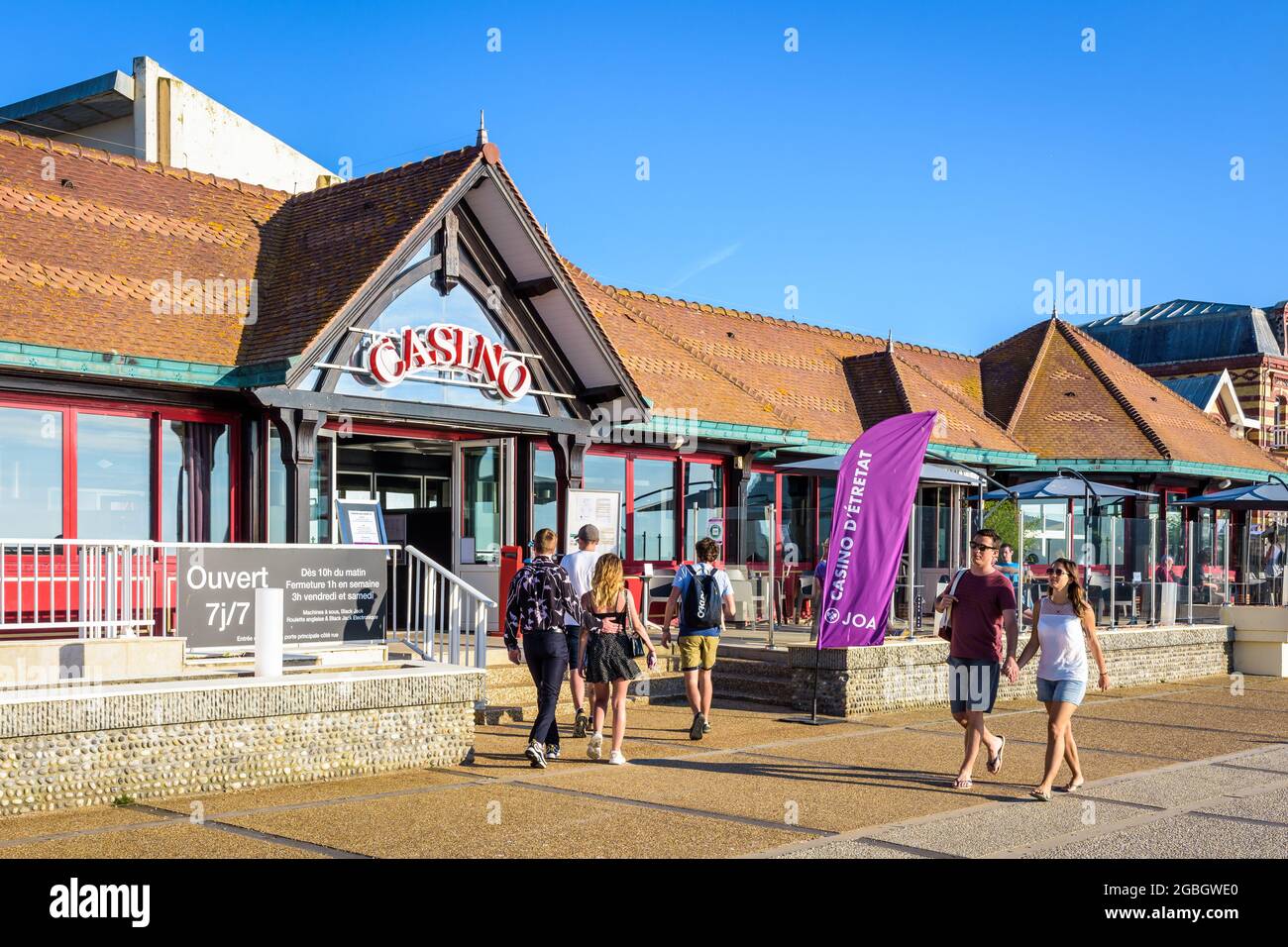 Junge Leute, die in Etretat, Frankreich, zu zweit oder mit Freunden spazieren, einige zum Casino, andere an einem sonnigen Tag am Meer entlang. Stockfoto