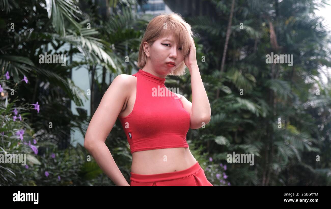 Junge Dame, asiatisches japanisches Model in einem roten Kleid im tropischen Bangkok Stockfoto