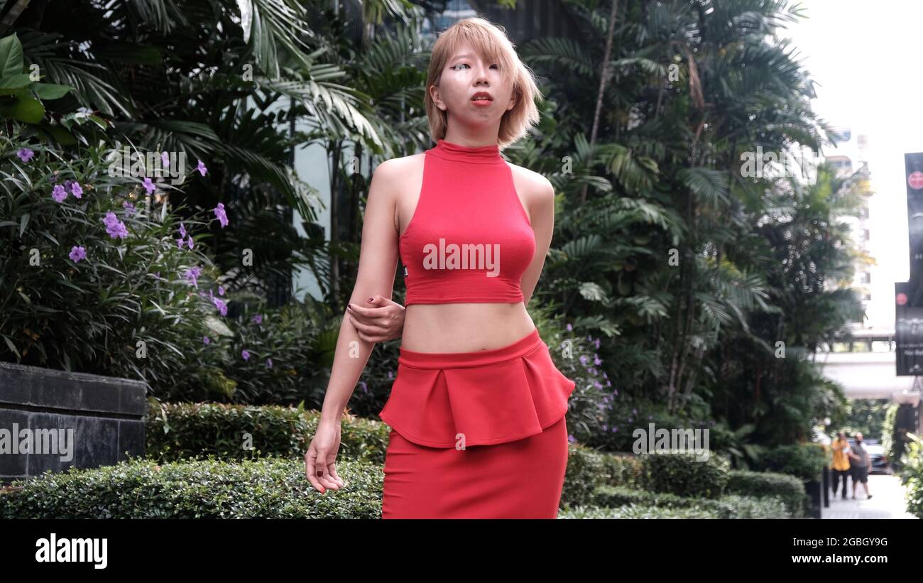 Junge Dame, asiatisches japanisches Model in einem roten Kleid im tropischen Bangkok Stockfoto