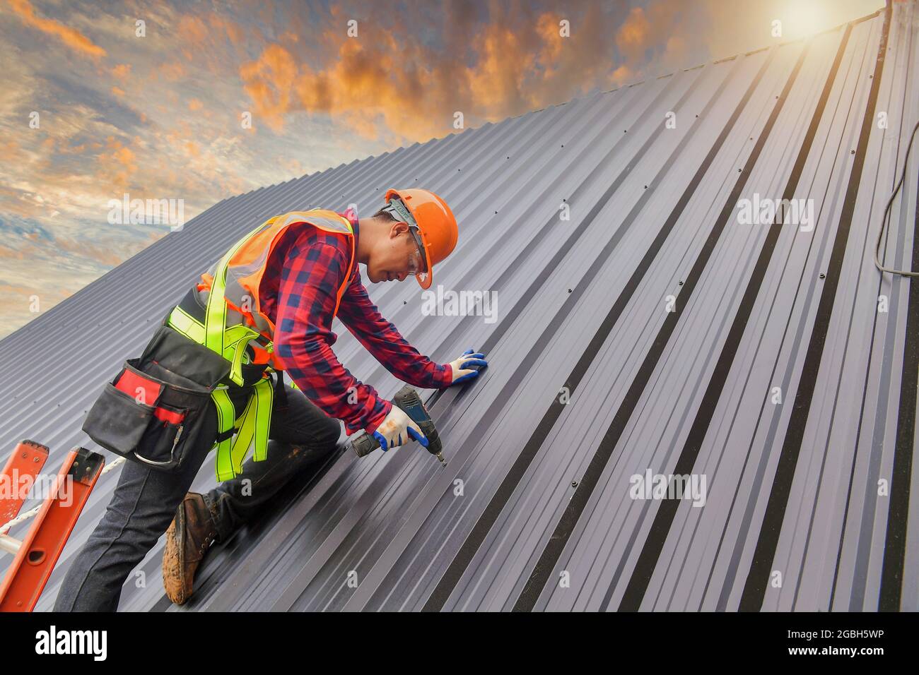 Bauarbeiter Montage von Metallblechen auf einem Dach, Thailand Stockfoto